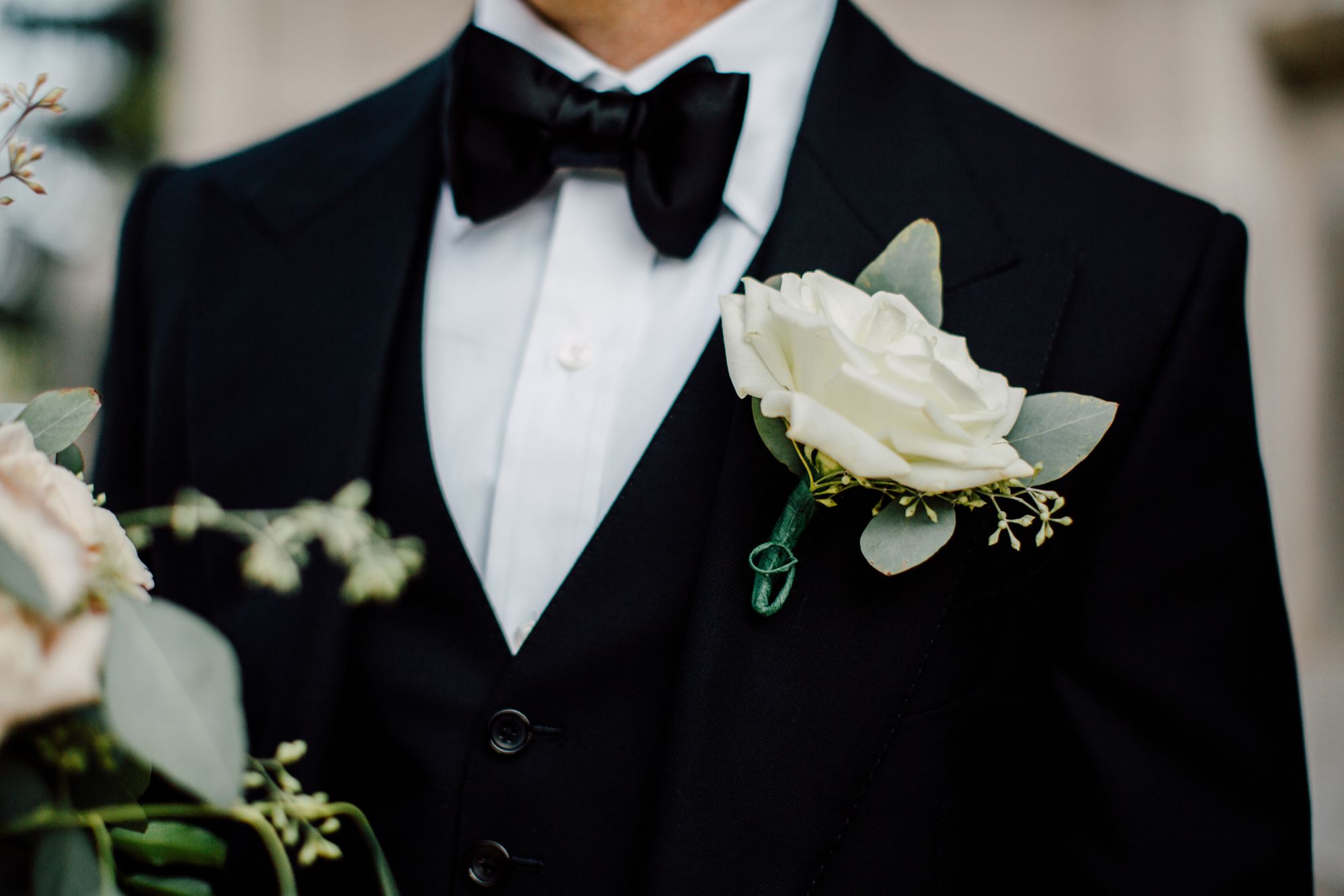 Ein Bräutigam im schwarzen Smoking mit einer weißen Blume am Revers.