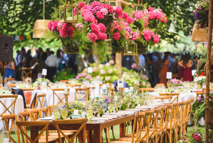 Ein Tisch in einem Garten mit rosa Blumen, die von der Decke hängen.