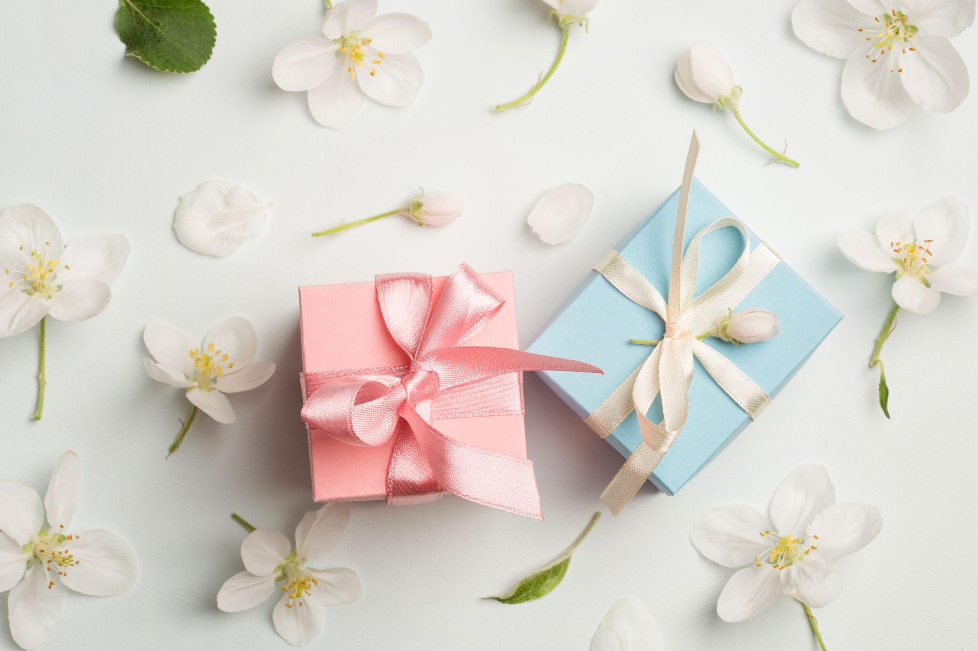 Zwei Geschenkboxen auf weißem Hintergrund mit weißen Blumen.