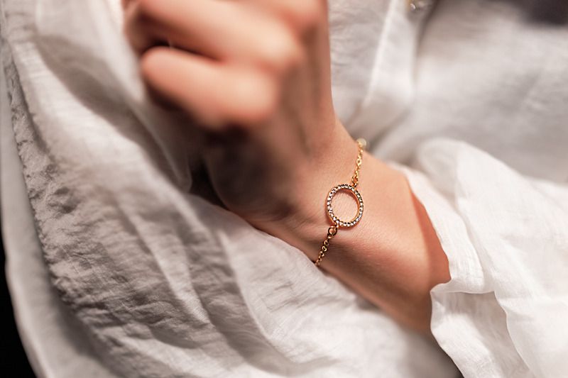 Eine Frau trägt ein goldenes Armband mit einem Diamanten darauf.