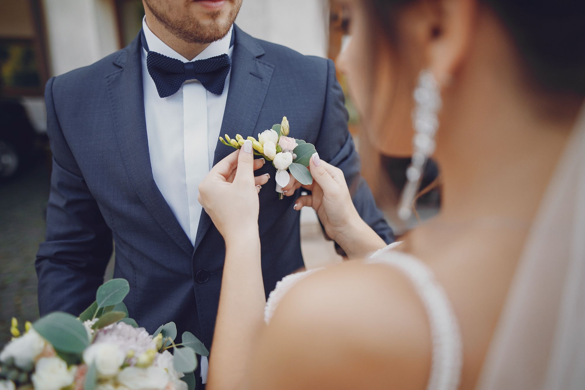 Braut befestigt Anstecker an Bräutigam auf ihrer Hochzeit