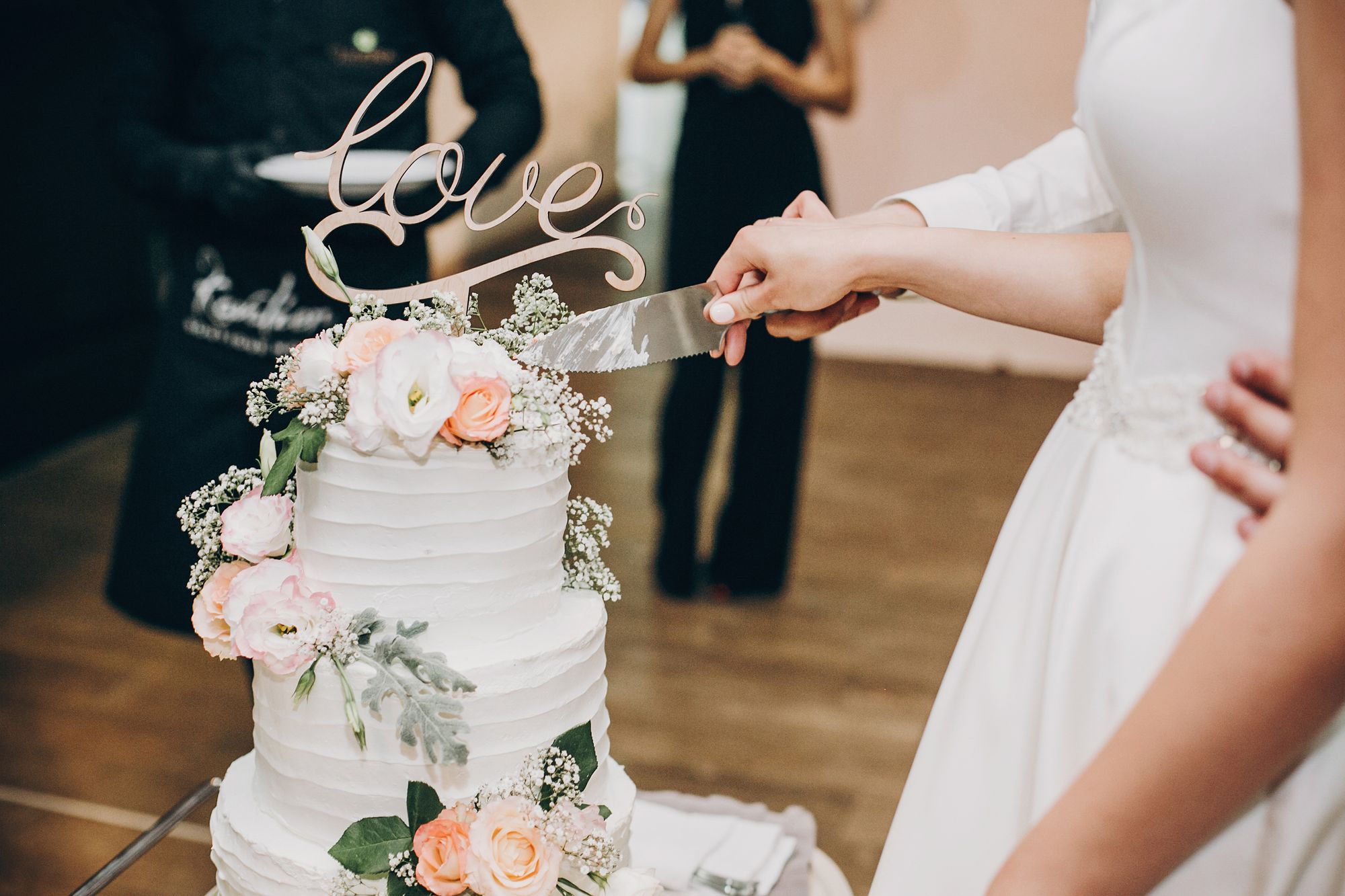 Brautpaar schneidet Hochzeitstorte mit Cake Topper an