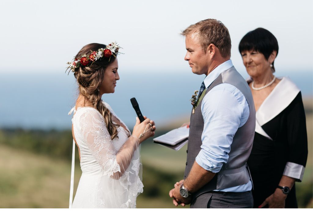 Eine Braut und ein Bräutigam geben sich vor dem Meer das Ja-Wort.