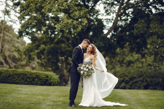 Eine Braut und ein Bräutigam küssen sich im Gras.