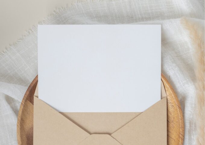 Ein Umschlag mit einem leeren Blatt Papier auf einer Holzplatte.