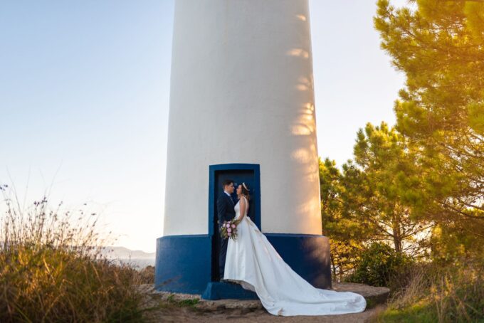 Ein Brautpaar posiert vor einem Leuchtturm.