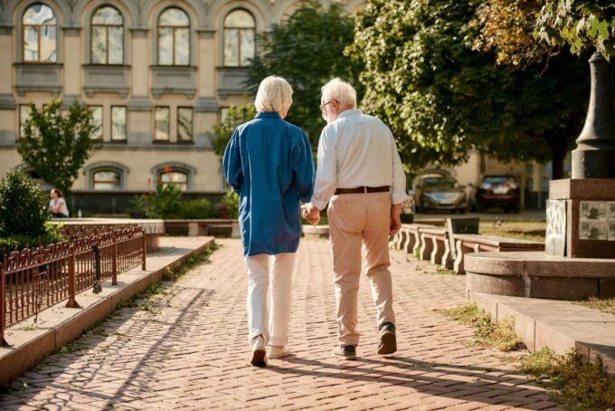 Ein älteres Paar geht einen gemauerten Gehweg entlang.