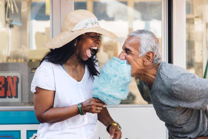 Ein älteres Paar lacht, während es Zuckerwatte isst.