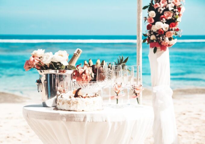 Ein Tisch am Strand mit Blumen und Champagner.