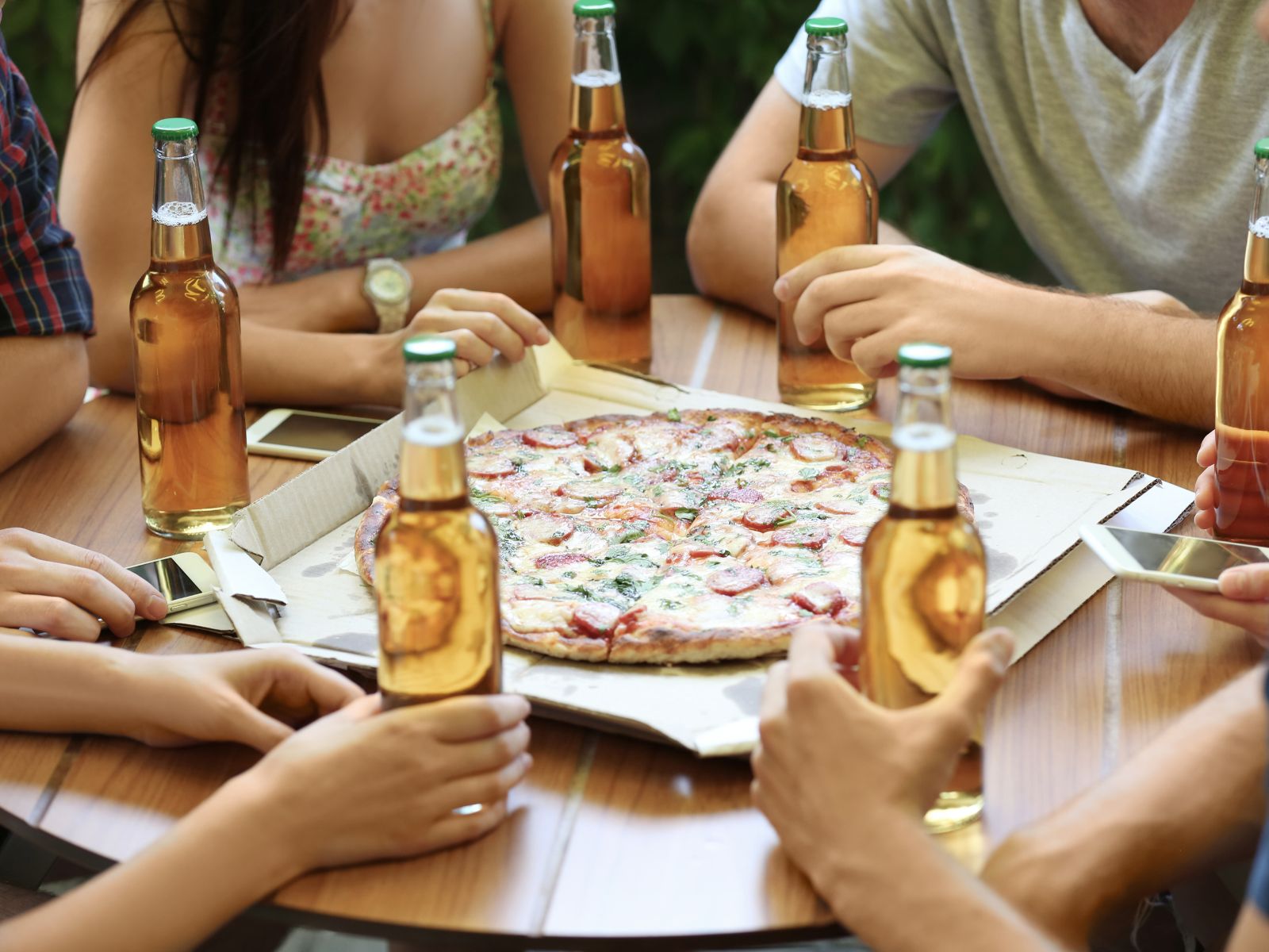 Freunde sitzen zusammen mit Bier und Pizza.
