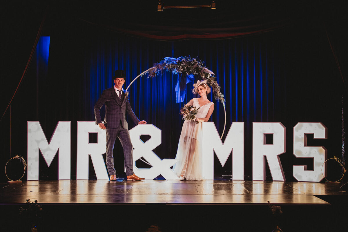 Eine Braut und ein Bräutigam stehen vor den Briefen von Herrn und Frau.