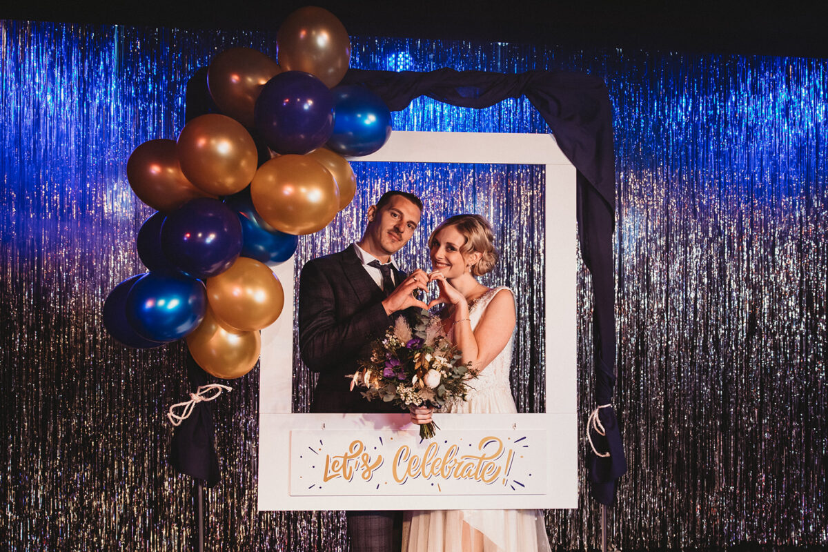 Eine Braut und ein Bräutigam posieren vor einem Rahmen mit Luftballons.