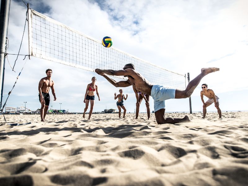 Menschen spielen Beach-Volleyball am Strand.