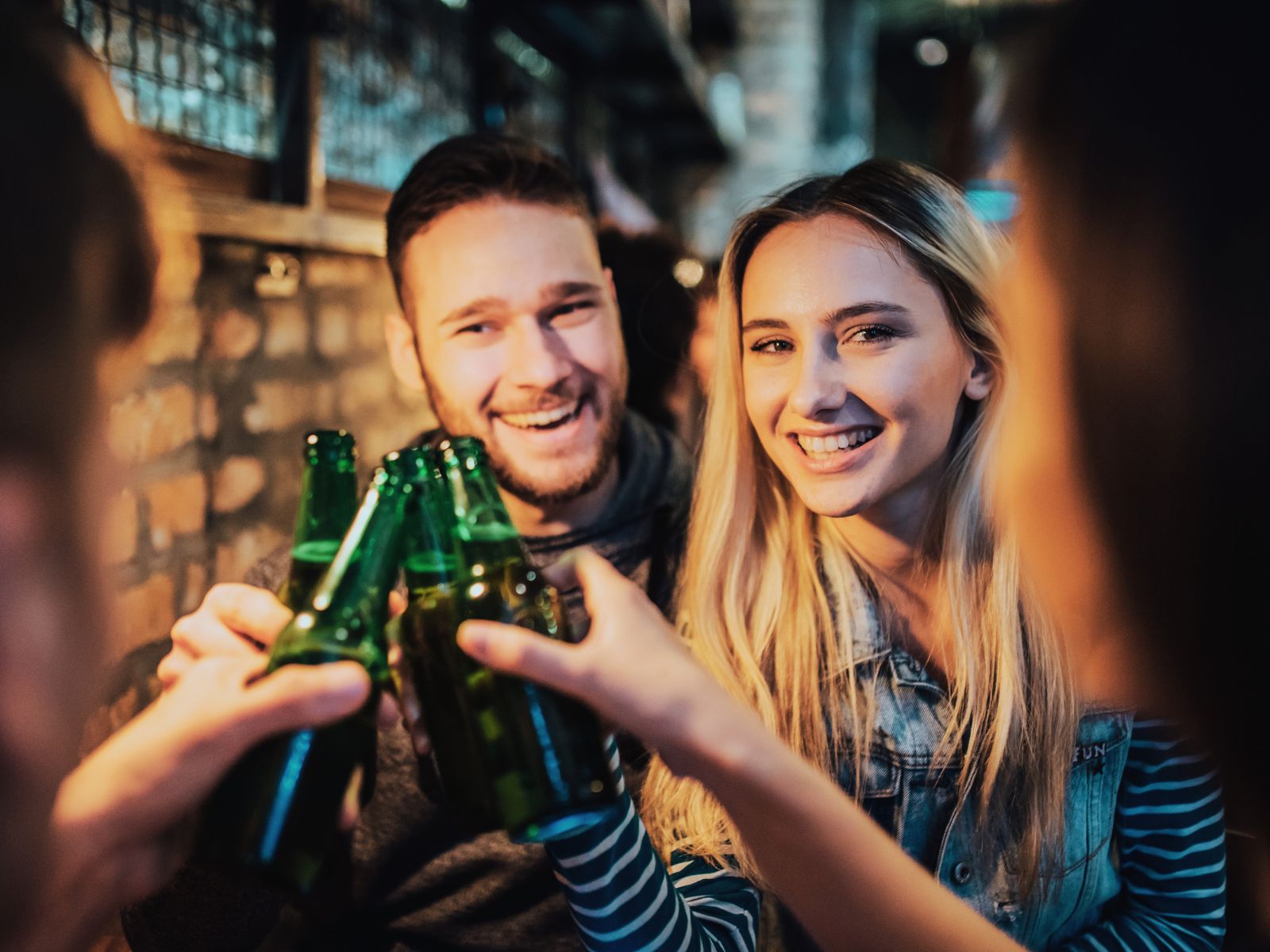 Das Bild zeigt, wie Freunde in fröhlicher Runde mit Bier anstoßen.