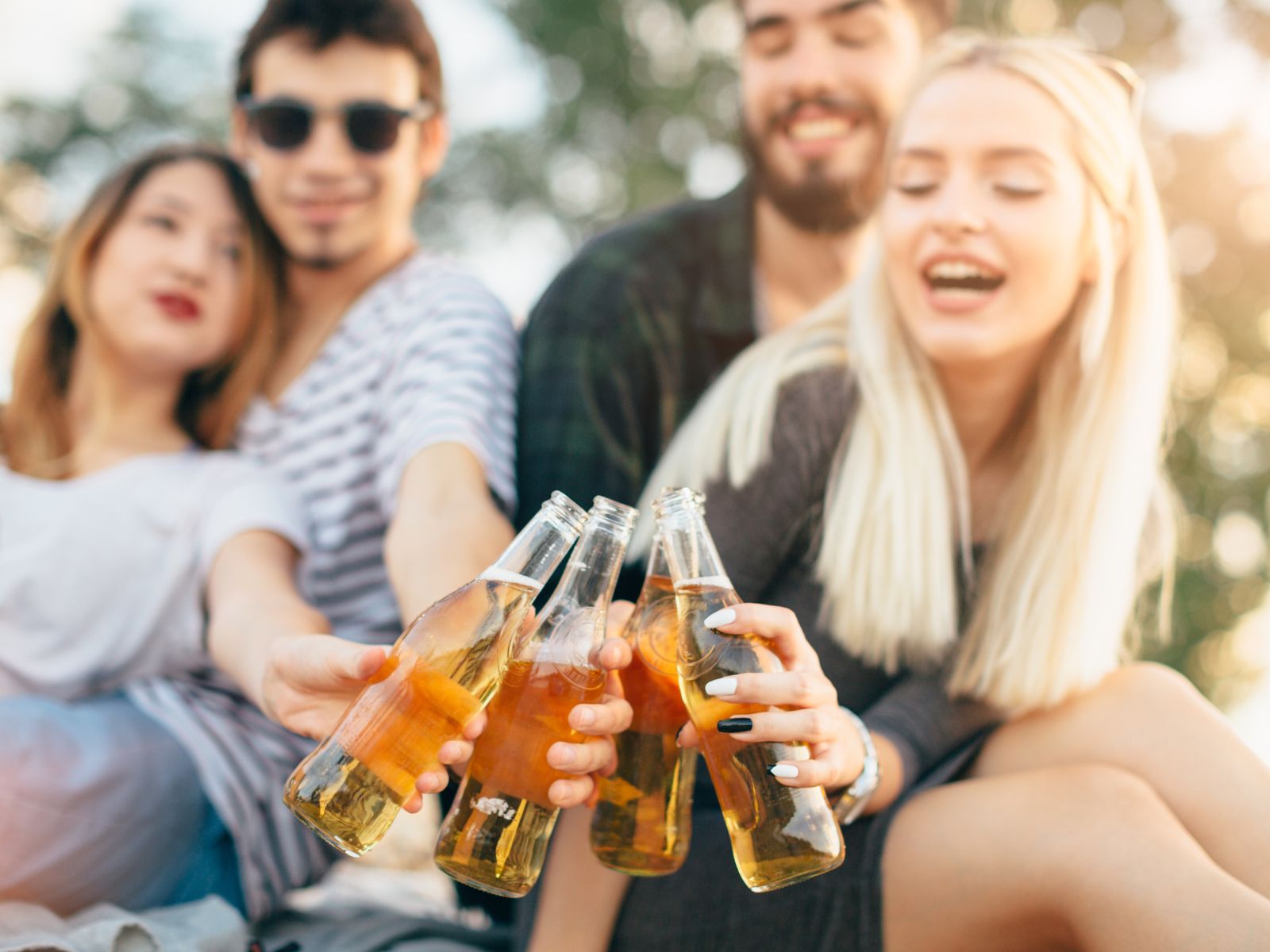 Freunde, die gemeinsam die schöne Atmosphäre draußen mit einem Bier in der Hand genießen.