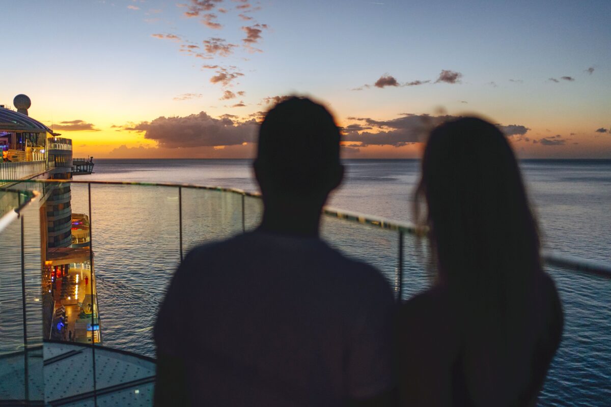 Paar hält sich an Deck eines AIDA Schiffes an der Reling, Blick aufs Meer.