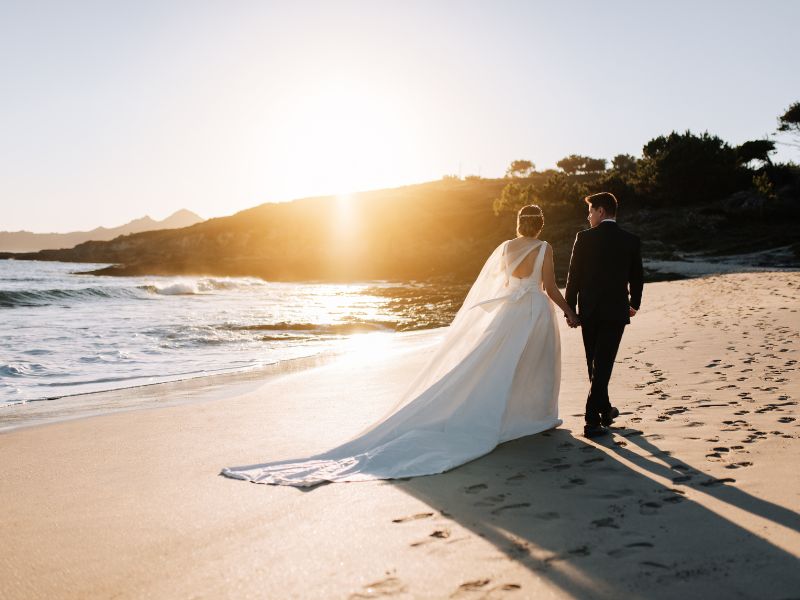 Brautpaar läuft bei Sonnenuntergang am Strand entlang