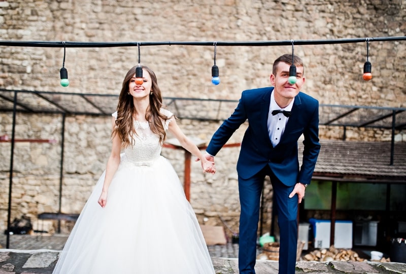 Eine Braut und ein Bräutigam halten Händchen und posieren mit der Lichterkette.