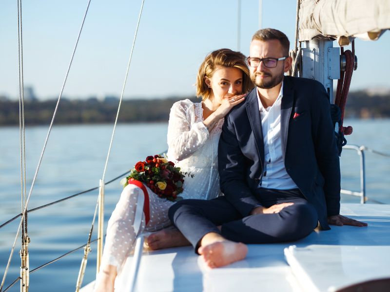 Brautpaar sitzt kuschelnd am Bug eines Segelschiffs