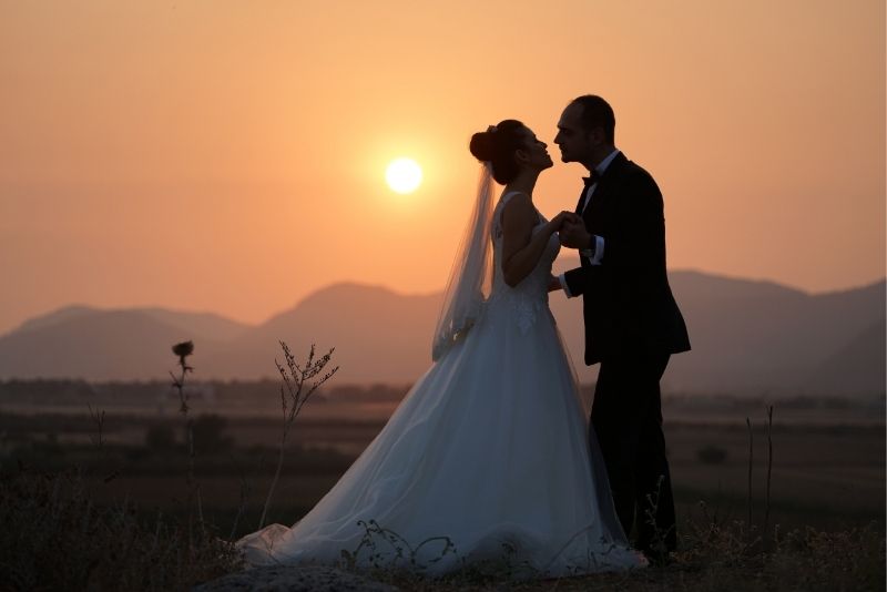 Das Brautpaar genießt den Sonnenuntergang auf einer Wiese.