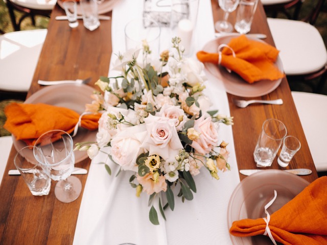 Dekorierter Hochzeitstisch mit Rosen und orangefarbenen Servietten