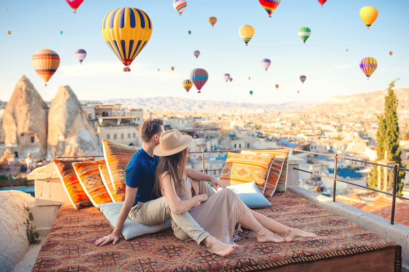 Junges Paar reist nach Kappadokien und beobachten von Dachterrasse Heißluftballons