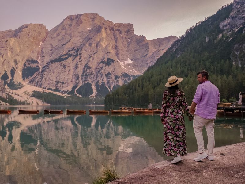 Paar steht am Ufer eines Sees mit Blick auf die Berge