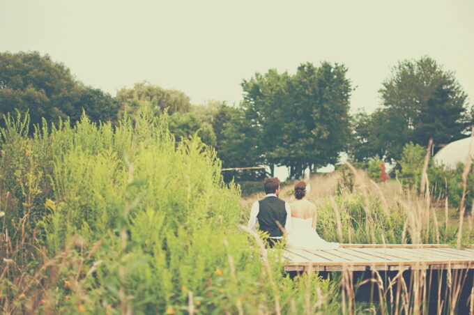 Eine Braut und ein Bräutigam sitzen auf einer Brücke in einem Feld.