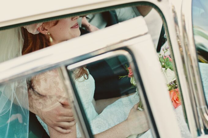 Eine Braut und ein Bräutigam sitzen auf dem Rücksitz eines Autos.