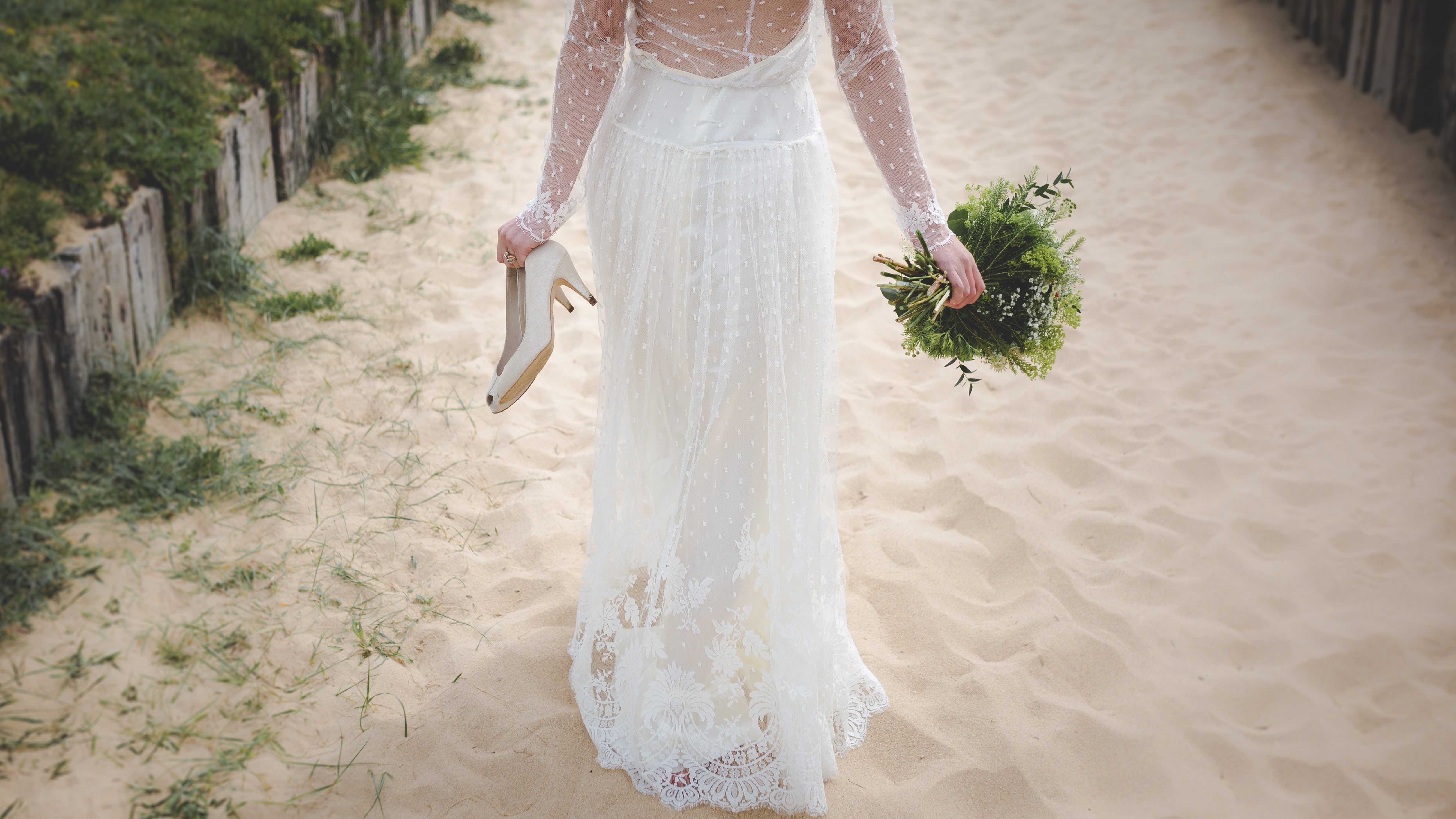 Eine Braut in einem weißen Hochzeitskleid, die auf dem Sand läuft.