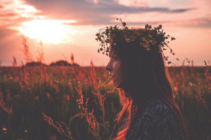 Ein Mädchen mit einer Blumenkrone auf einem Feld bei Sonnenuntergang.