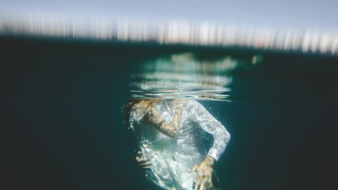 Eine Frau in einem weißen Kleid schwimmt unter Wasser.