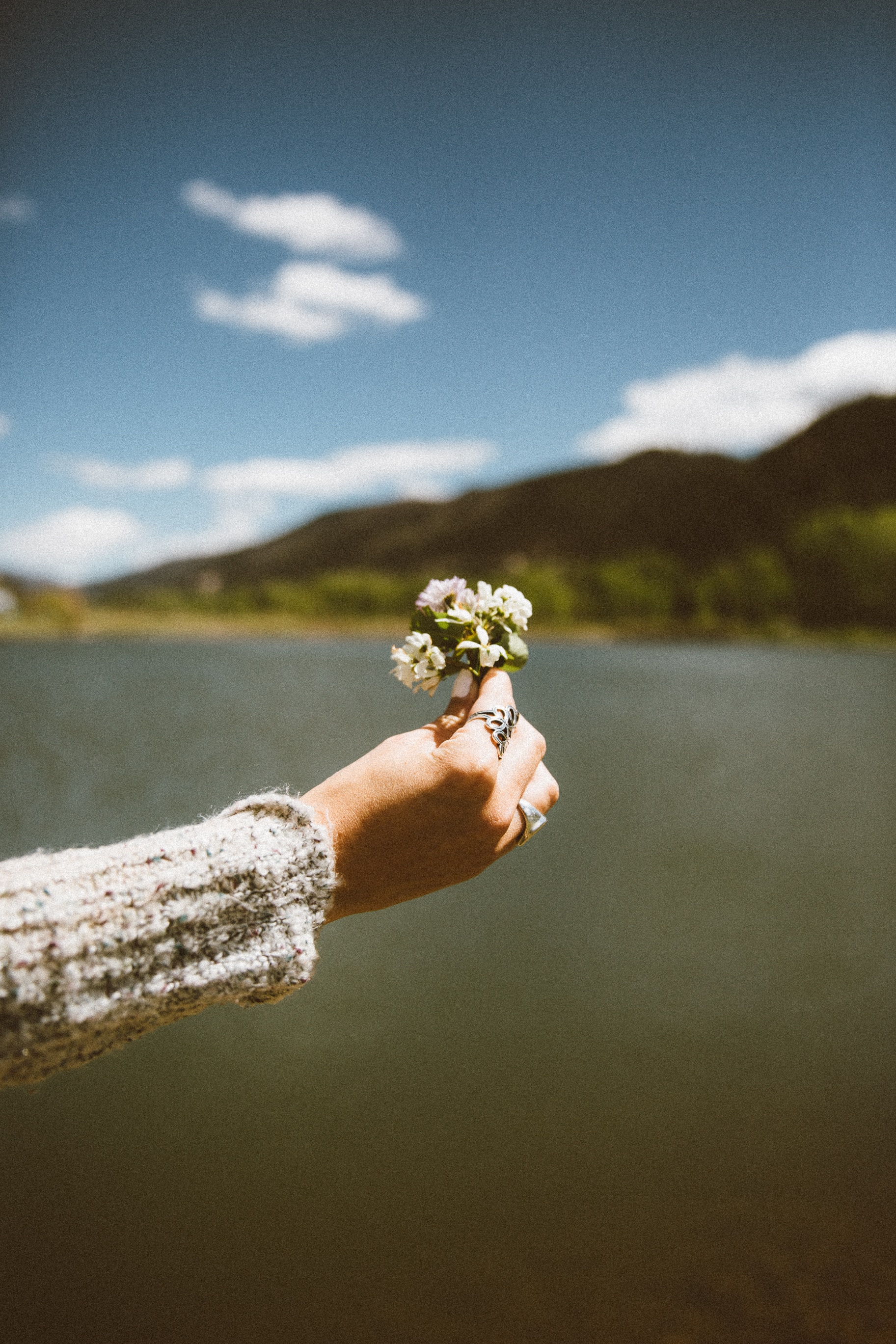 Eine Frau hält eine Blume vor einem See.