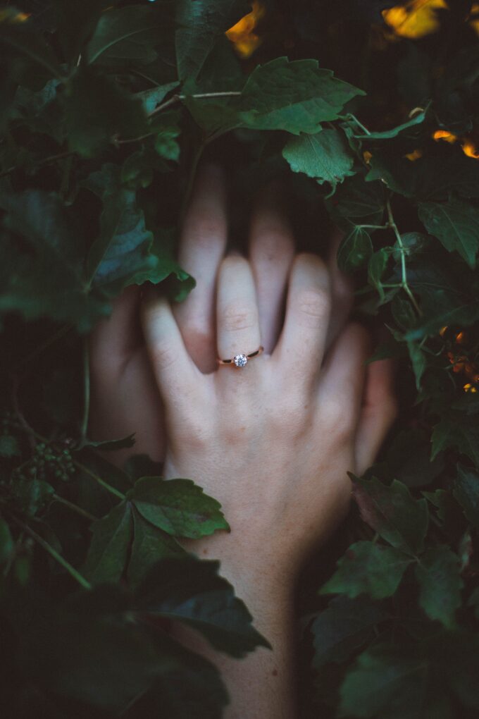 Die Hände einer Frau sind von grünen Blättern umgeben.