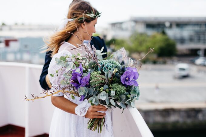 Eine Braut und ein Bräutigam halten ihren Hochzeitsstrauß auf einem Boot.