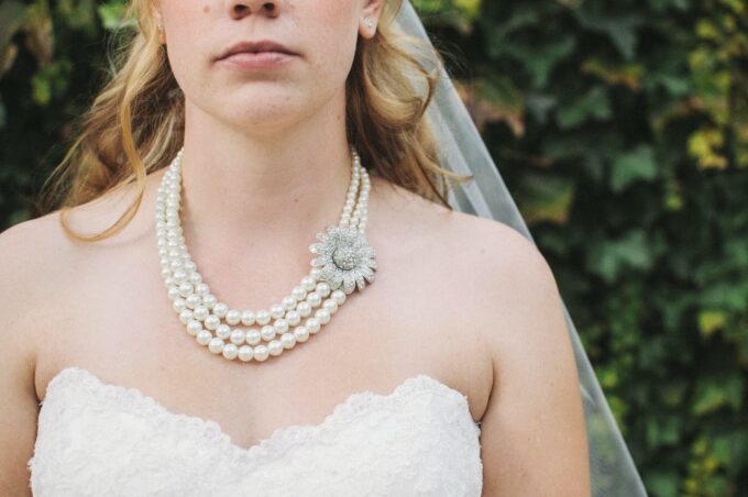 Eine Braut trägt eine Perlenkette und einen Schleier.