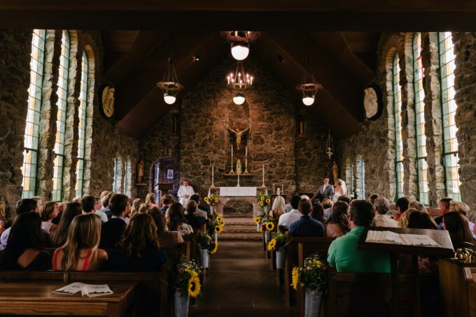 Eine Hochzeitszeremonie in einer Kirche mit Menschen, die in Kirchenbänken sitzen.