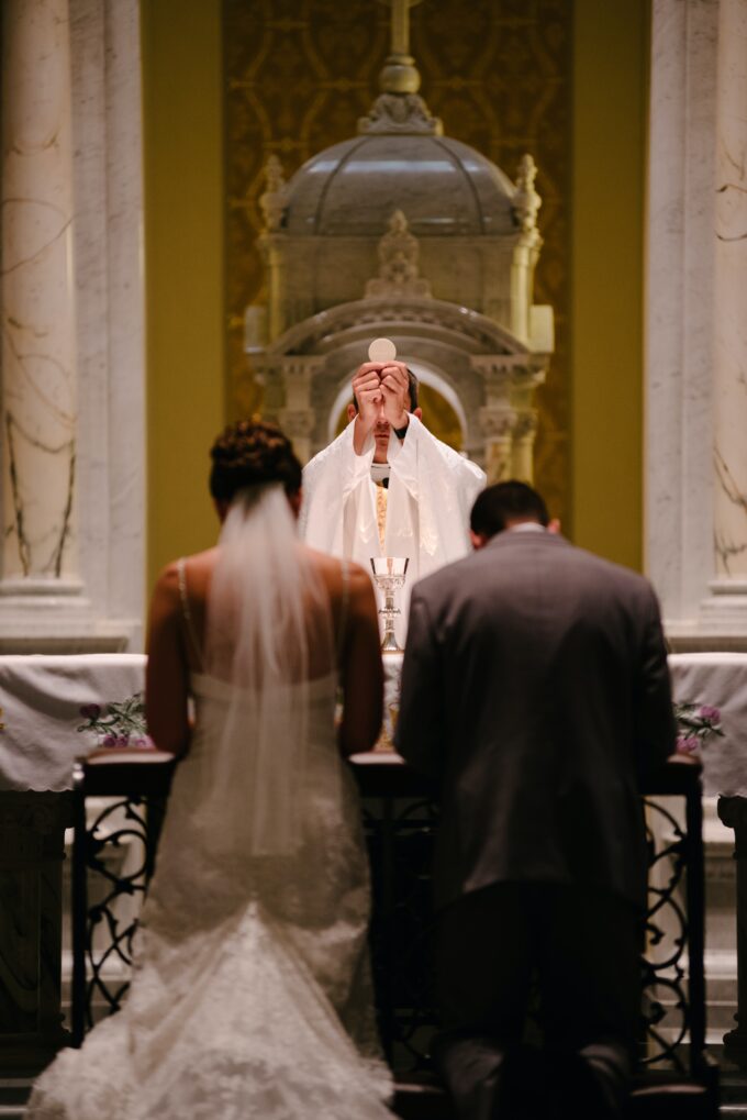 Ein Priester betet vor einem Brautpaar.