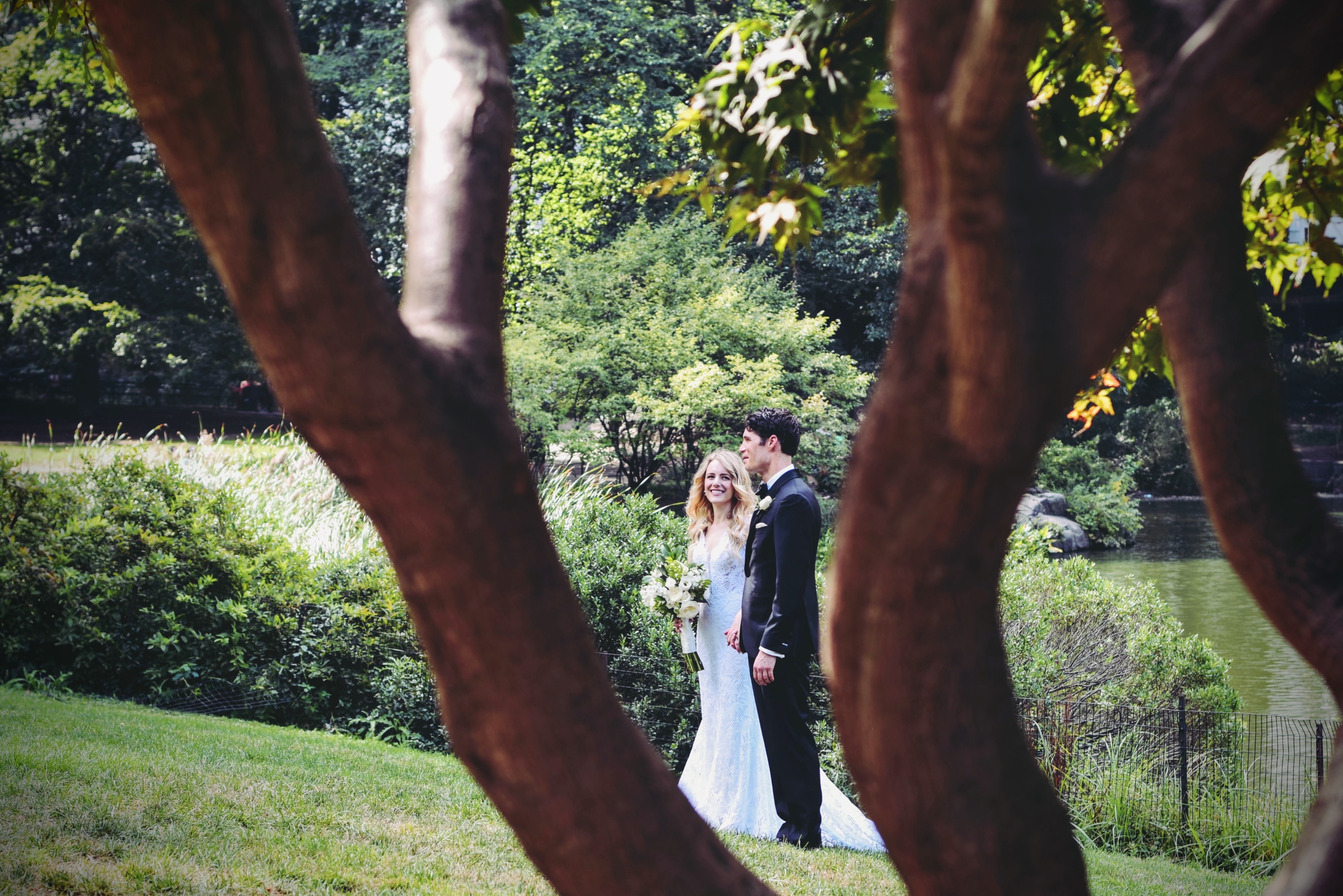 Eine Braut und ein Bräutigam stehen unter Bäumen in einem Park.