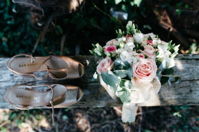 Ein Rosenstrauß und ein Paar Schuhe liegen auf einem Baumstamm.