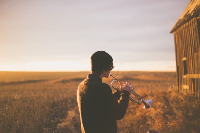 Ein Mann spielt Trompete vor einer Scheune.