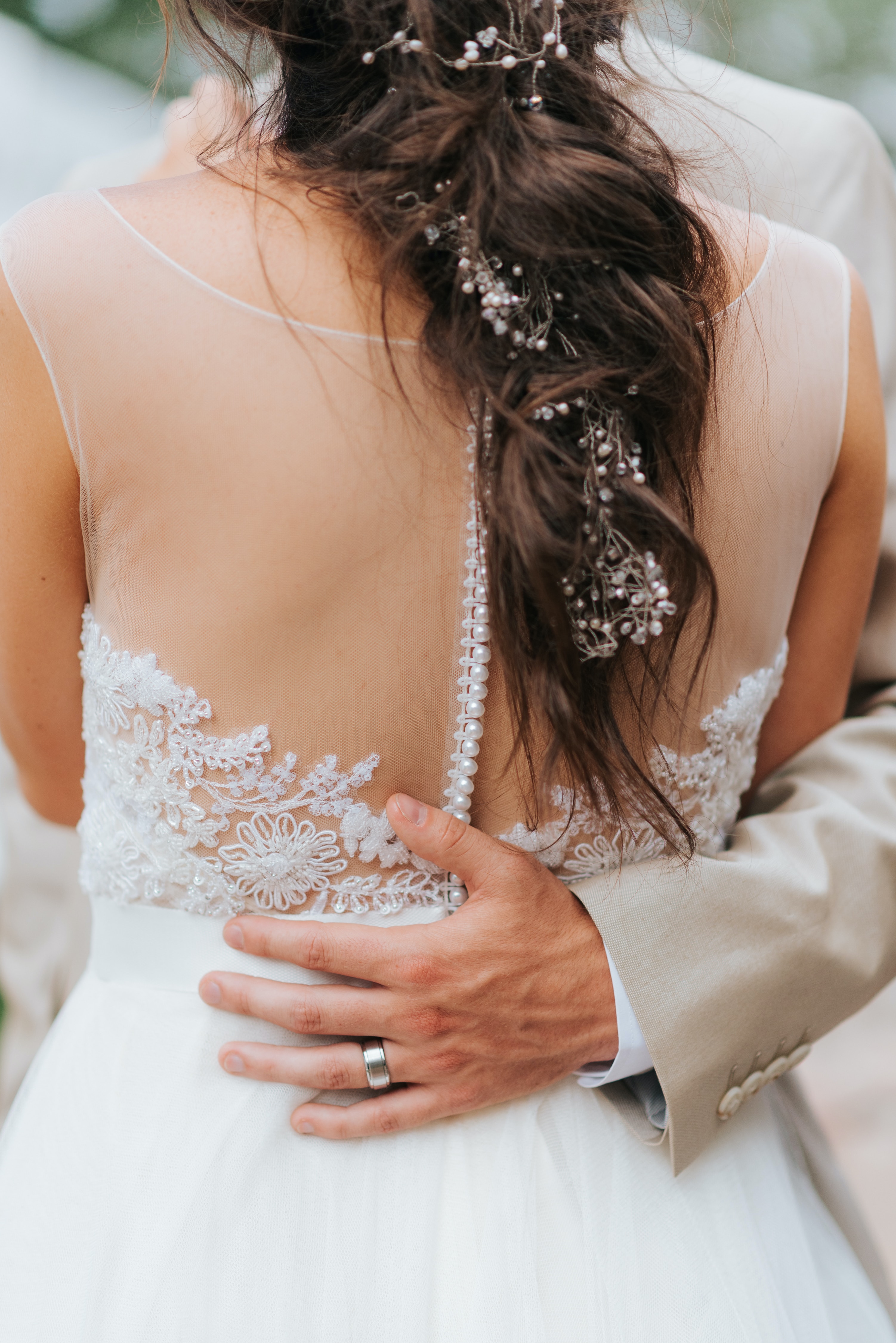 Eine Braut in einem weißen Hochzeitskleid hält die Hand ihres Mannes.
