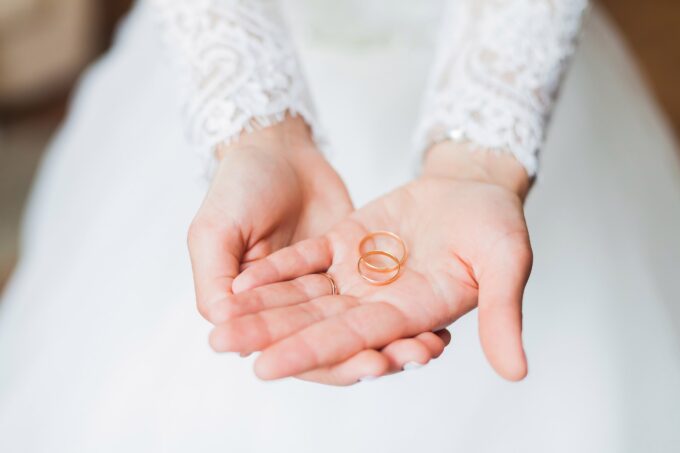 Eine Braut hält zwei Eheringe in ihren Händen.