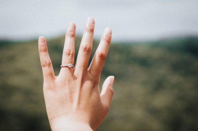 Die Hand einer Frau mit einem Diamantring darauf.