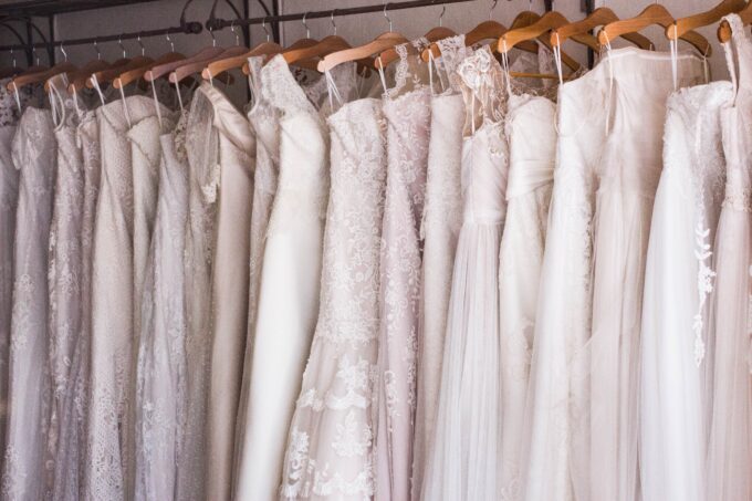 Eine Reihe Brautkleider, die an einem Kleiderständer hängen.