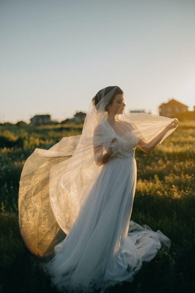 Eine Braut auf einem Feld, ihr Schleier weht im Wind.