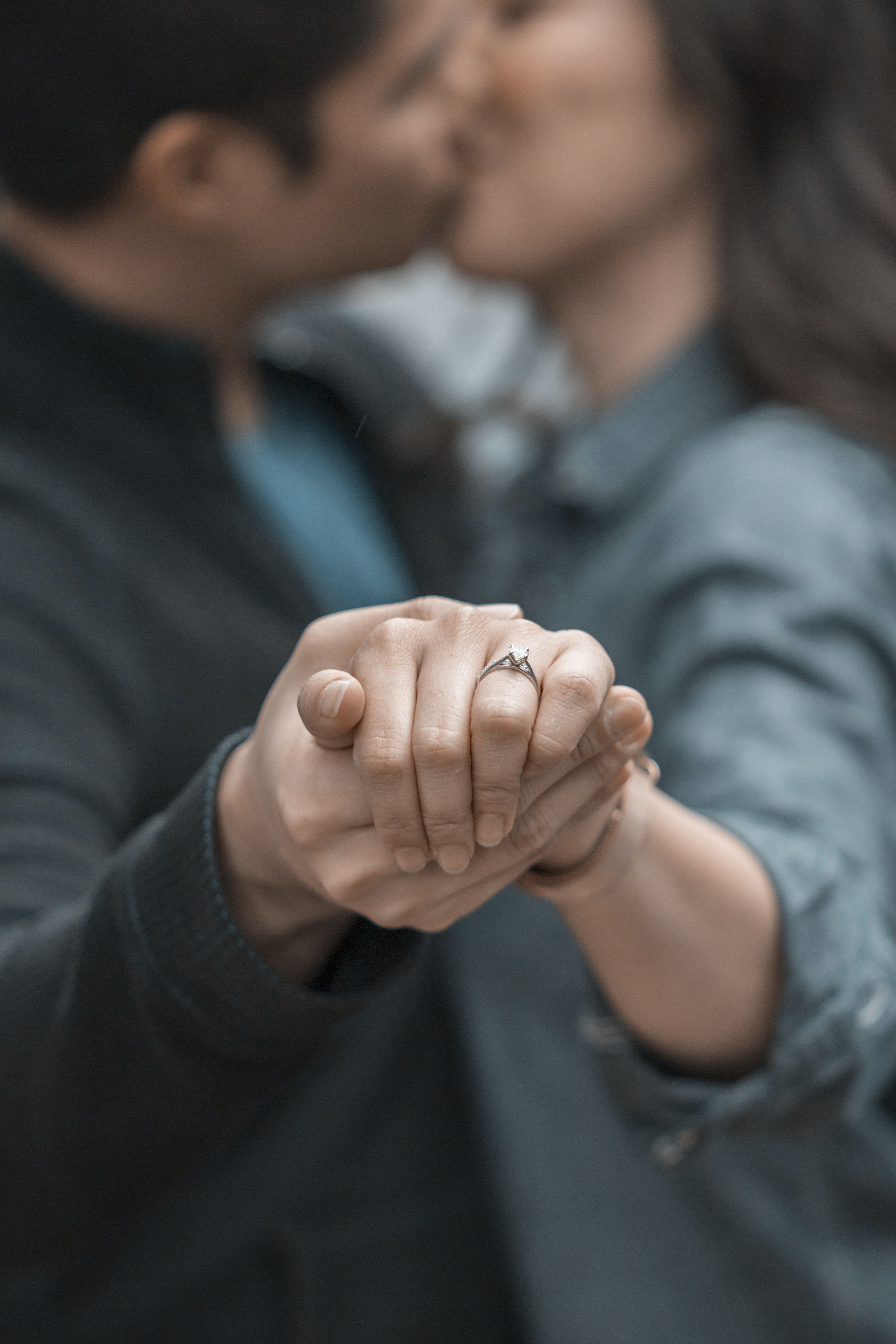Ein Mann und eine Frau küssen sich, während sie Verlobungsringe in der Hand halten.