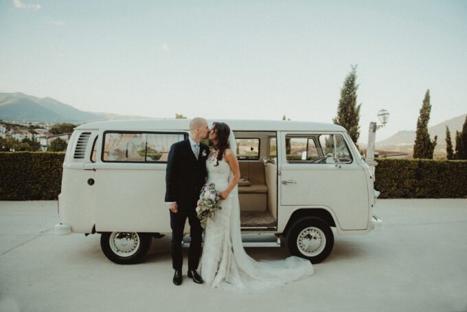 Eine Braut und ein Bräutigam posieren vor einem Oldtimer-VW-Bus.
