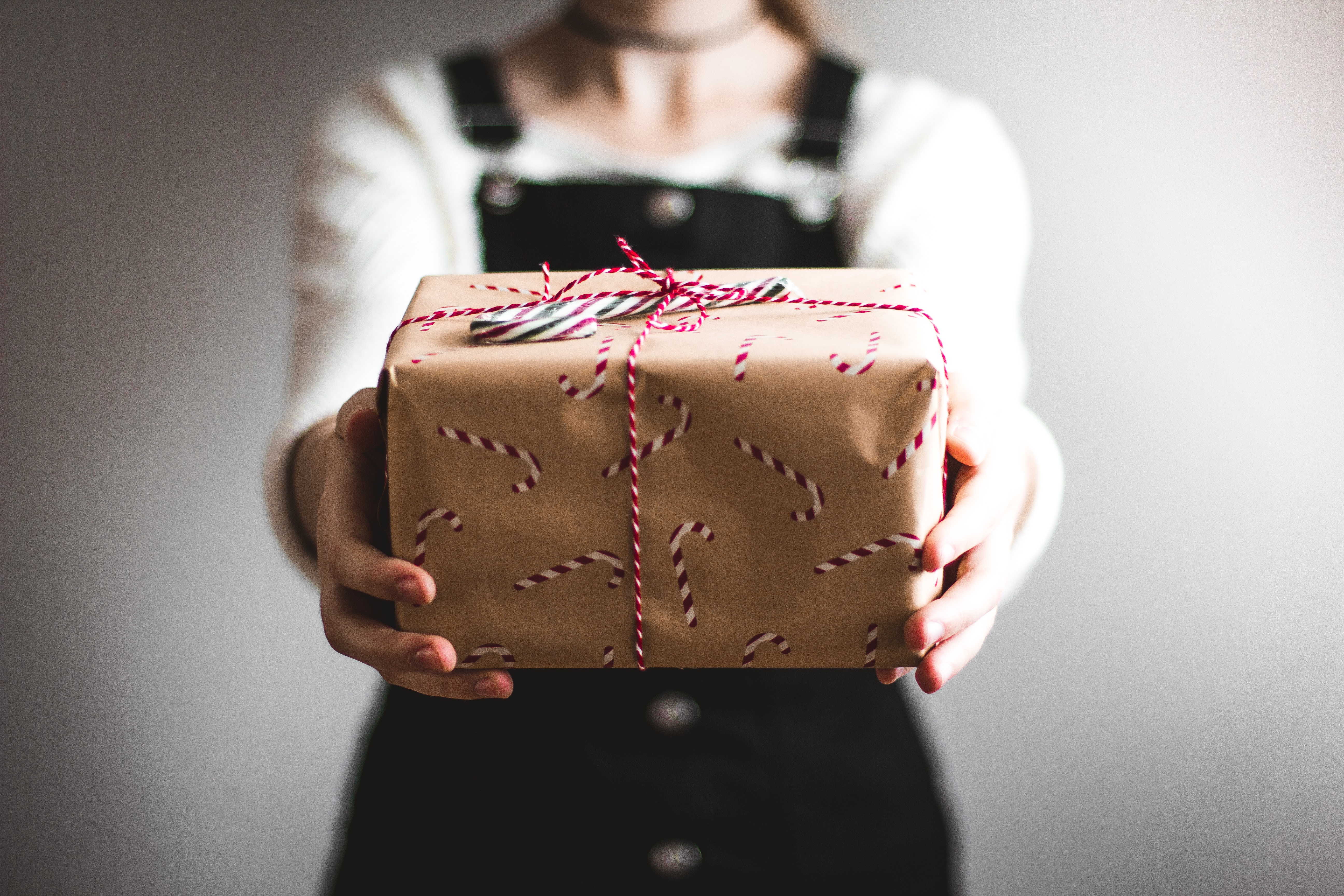 Eine Frau hält ein in braunes Papier eingewickeltes Geschenk.