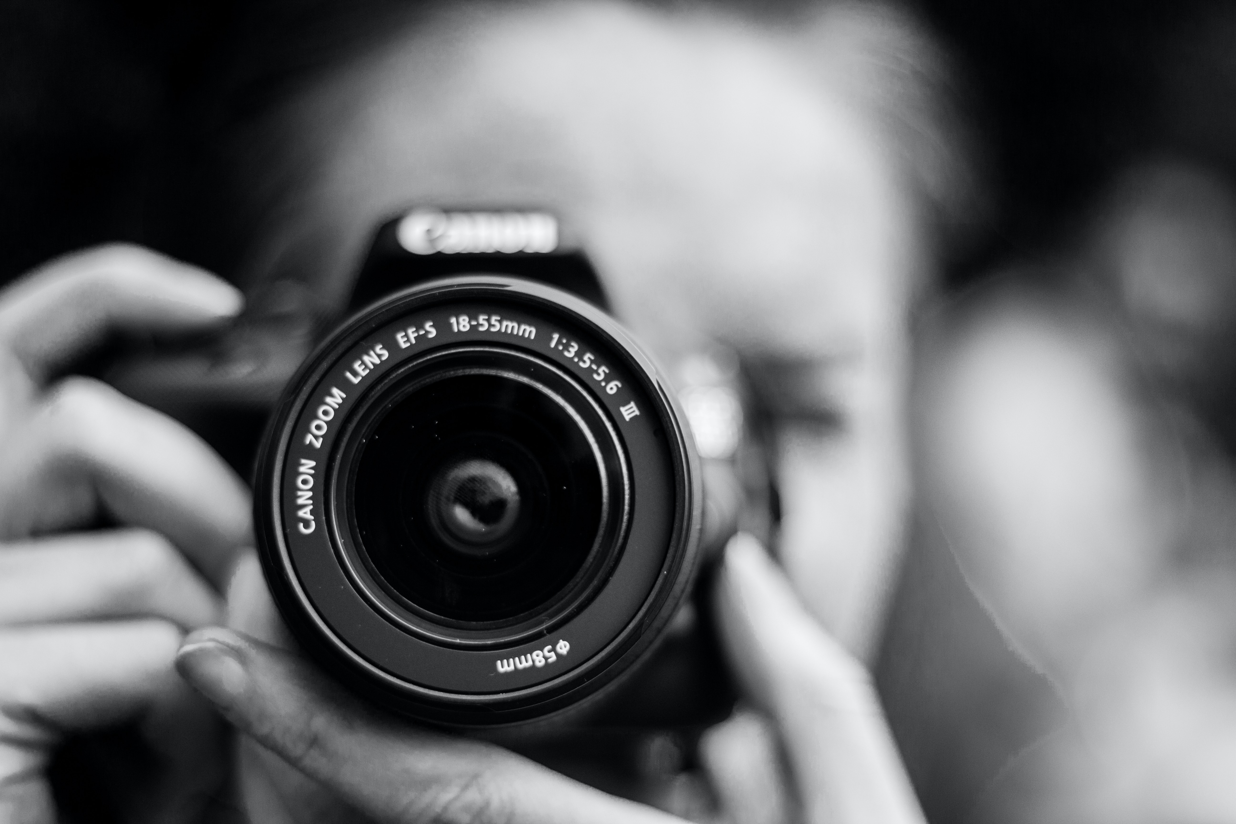 Ein Schwarz-Weiß-Foto einer Person, die eine Kamera hält.